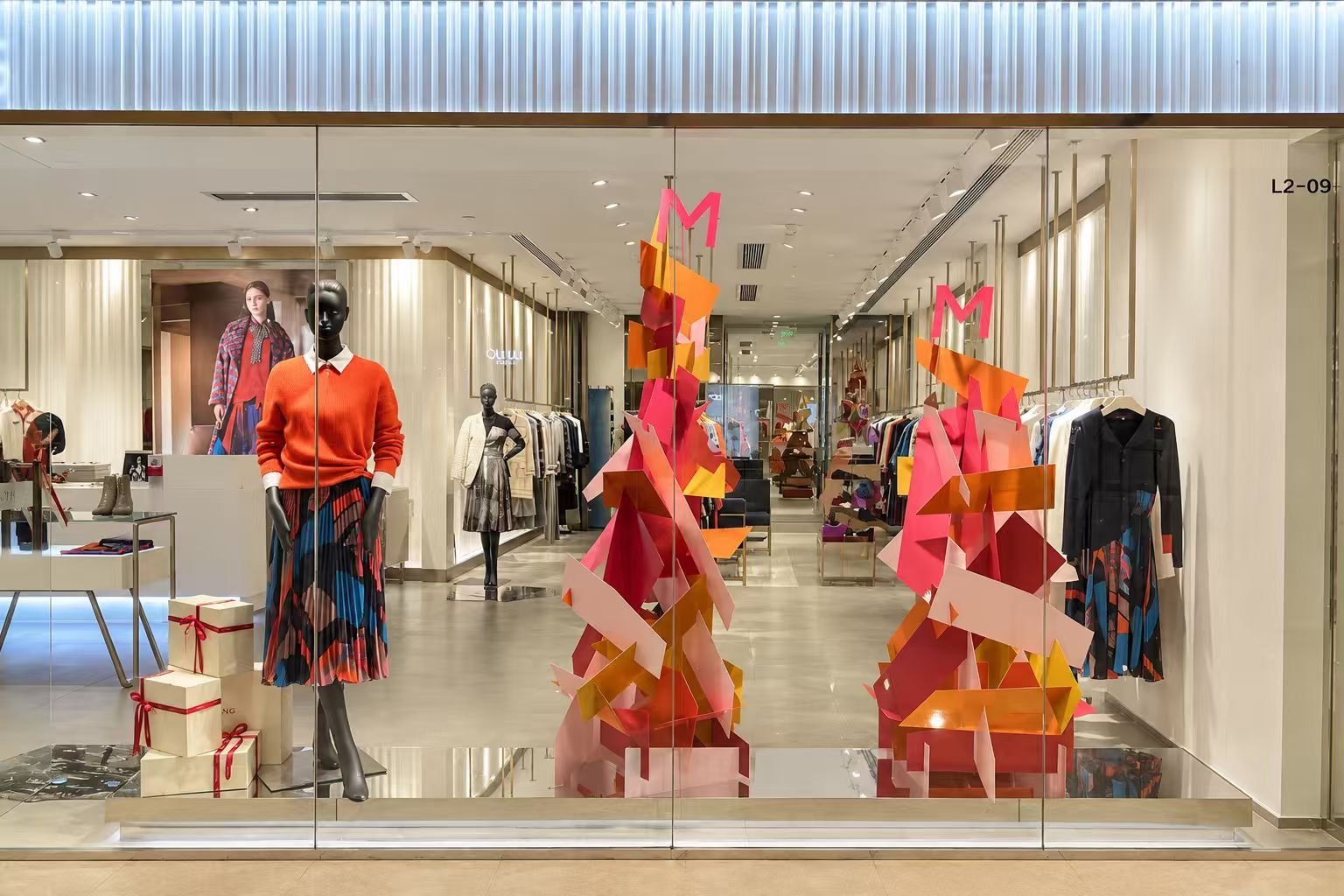 Store window with faceted coloured sculptures between mannequins
